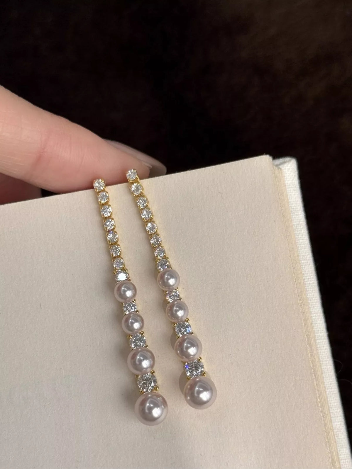 Gold-tone long pearl-like bead and clear stone drop earrings — detail view