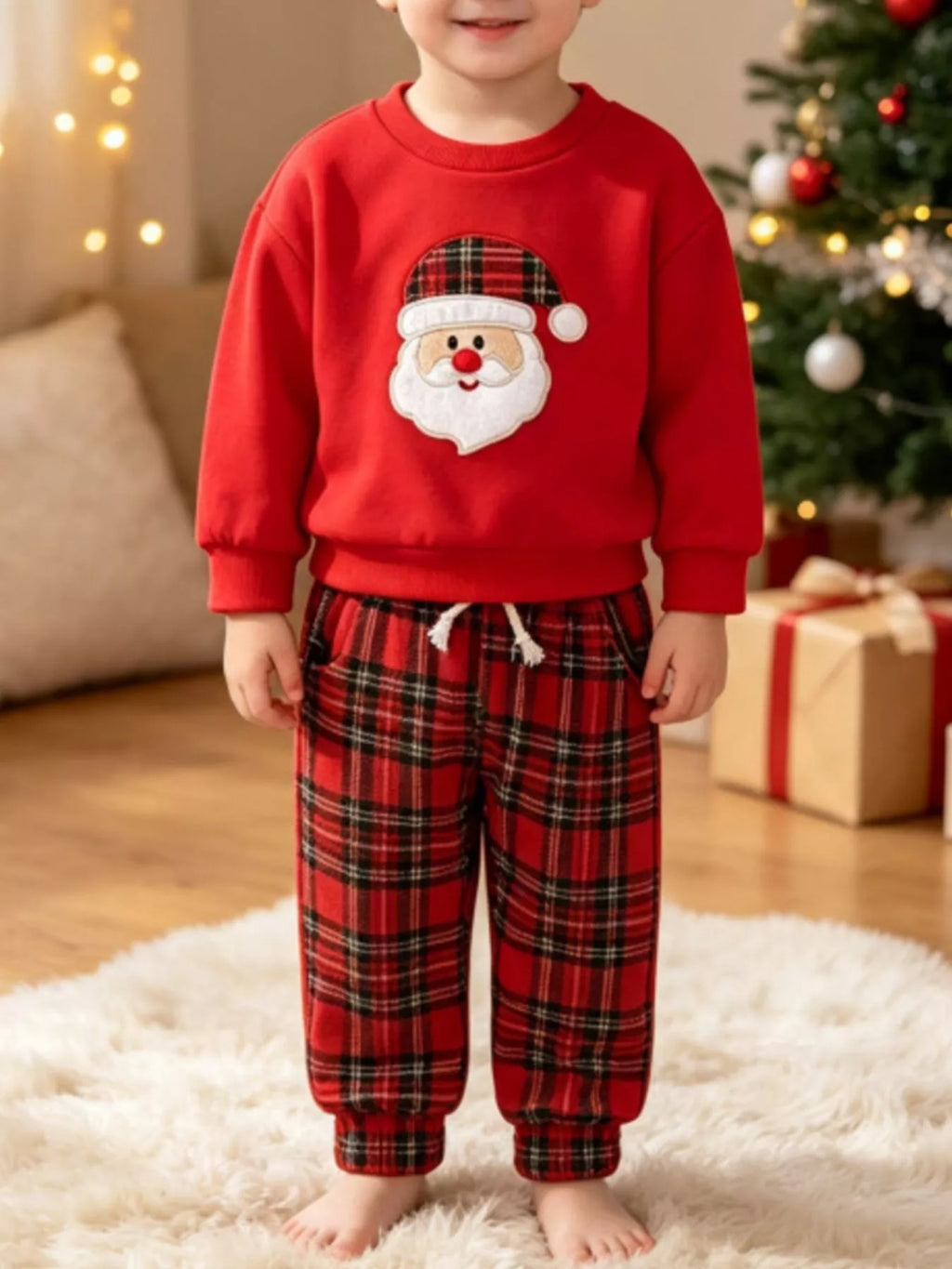 Children’s red Santa graphic sweatshirt and red plaid pants worn by a child