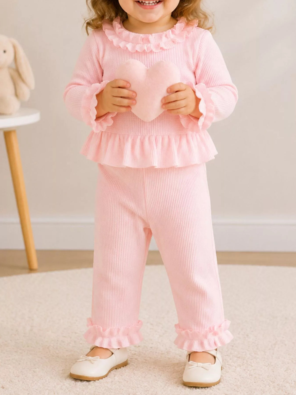Child modeling the pink peplum top and ruffle-hem pants set.