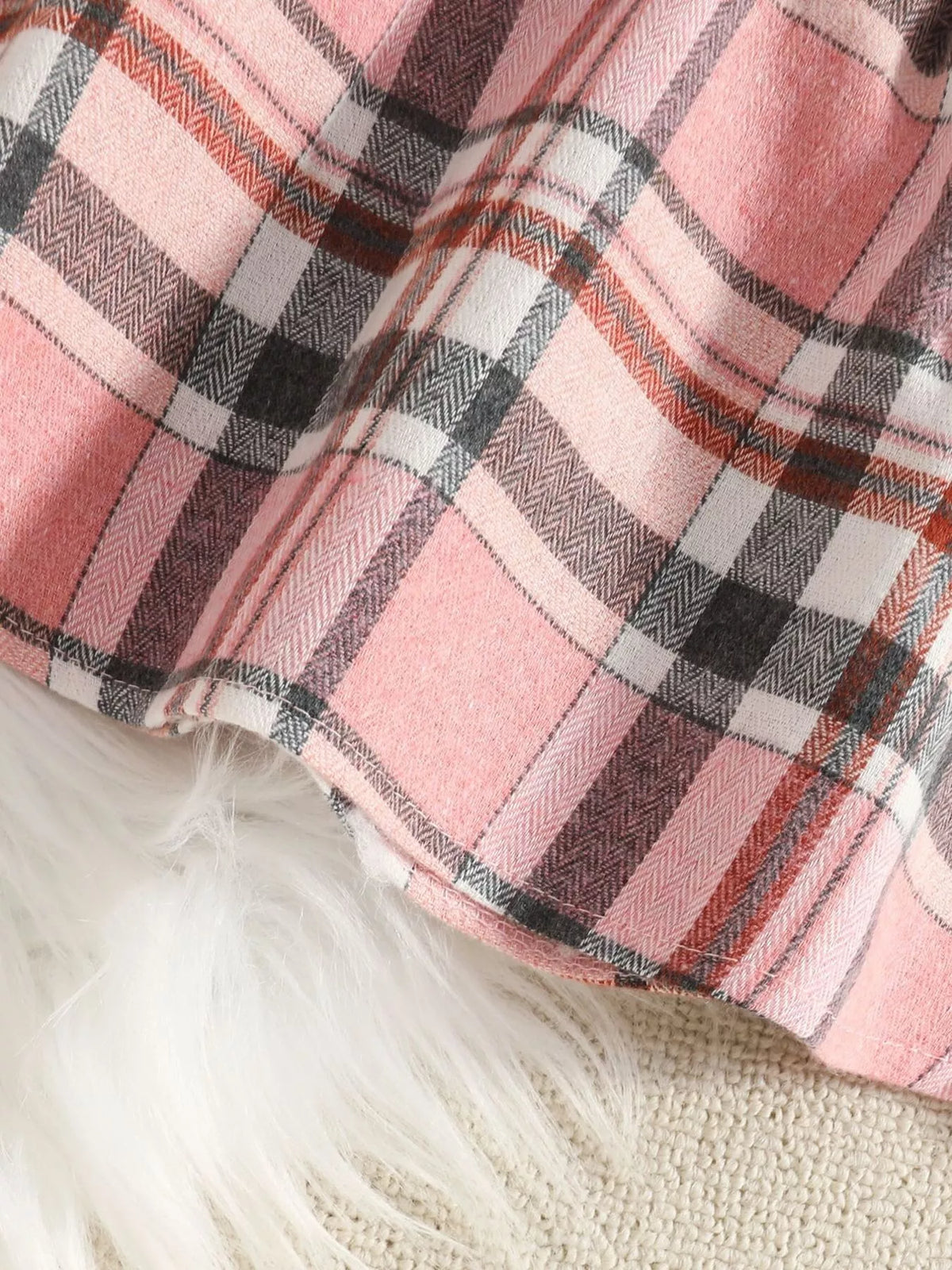 Close-up of the pink plaid skirt's stitched hem.