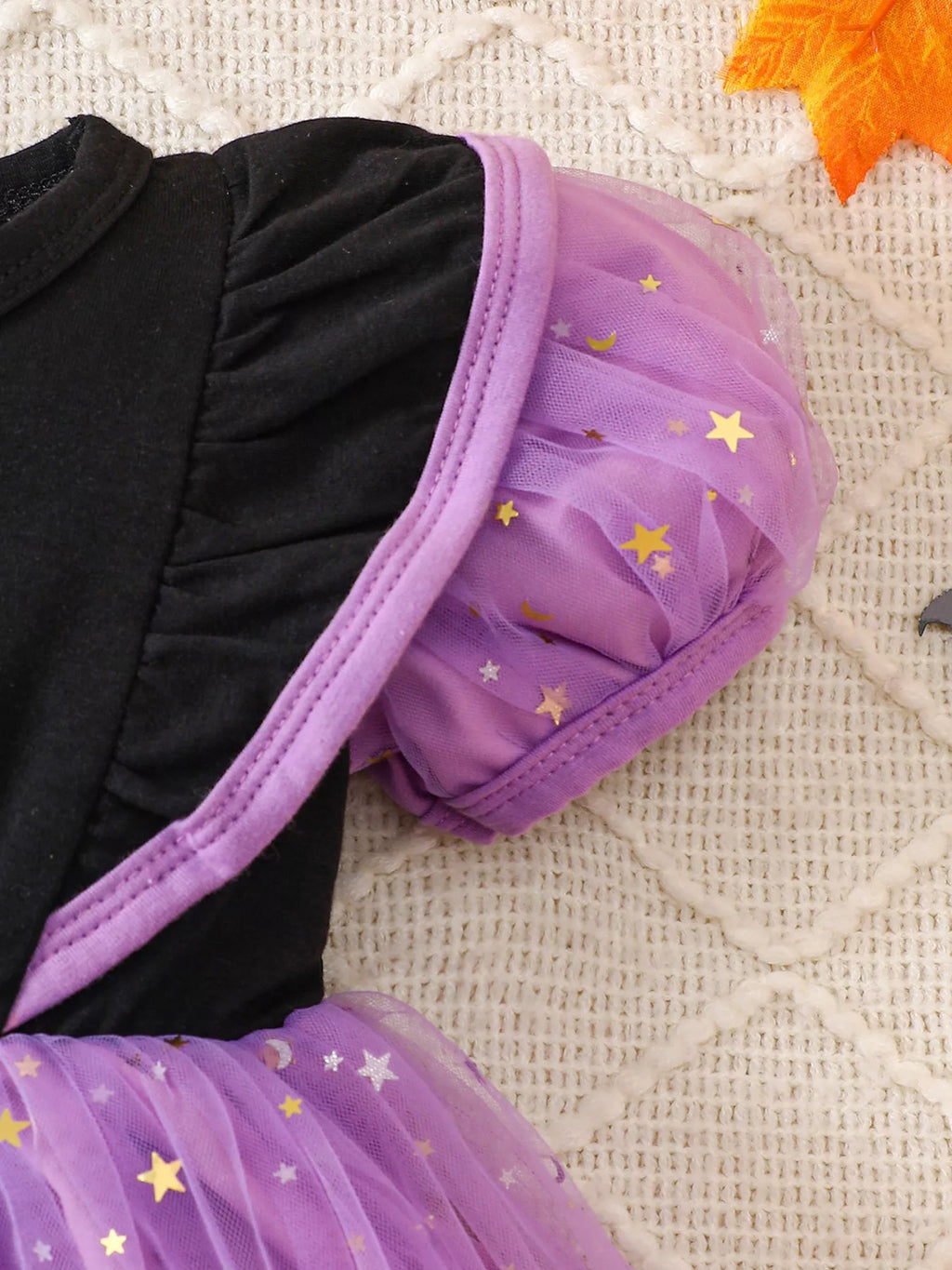 Close-up of the dress's purple puff sleeve and black shoulder.