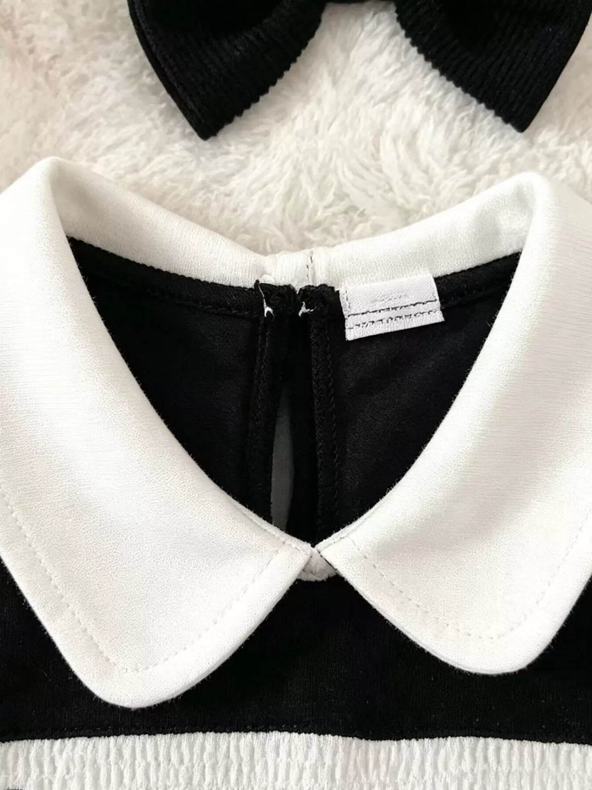 Close-up of the black romper's white rounded collar and back neckline zipper.