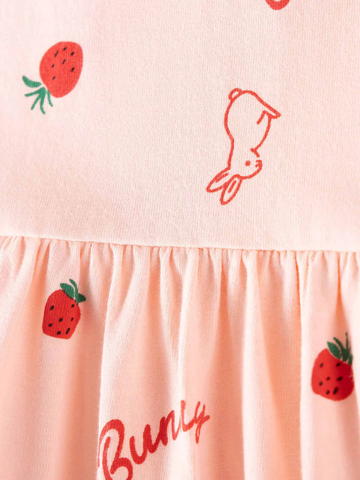 Close-up of the strawberry and bunny print at the gathered waist of the pink dress.
