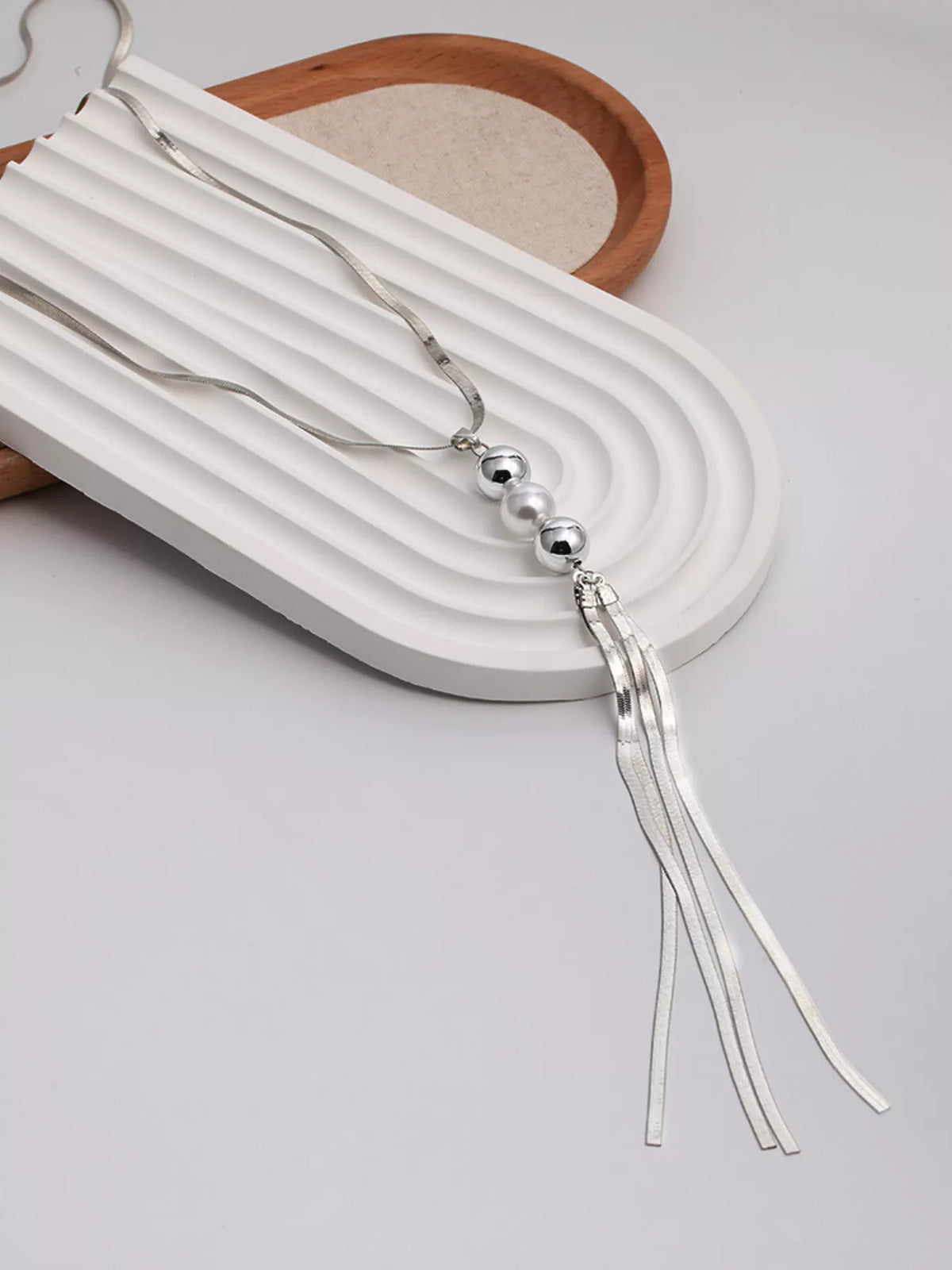 Long silver-tone necklace with bead accents and chain tassel — tassel detail