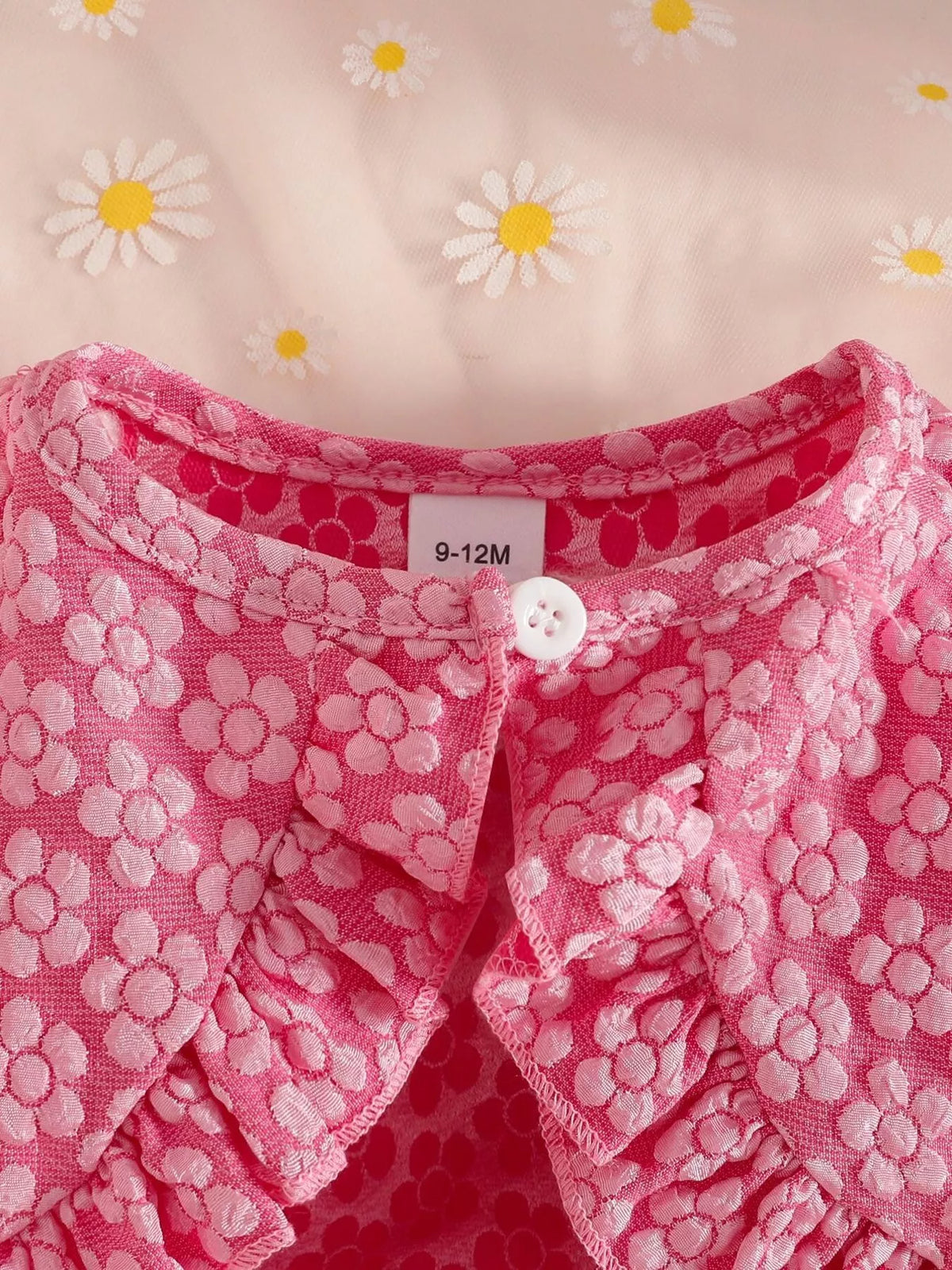 Close-up of the pink floral jacket's neckline, button and gathered trim.