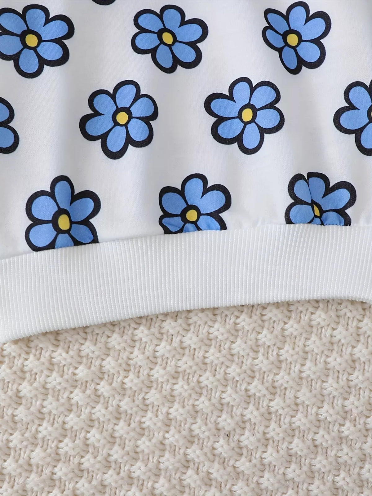 Close-up of the white blue-flower sweatshirt's ribbed hem.
