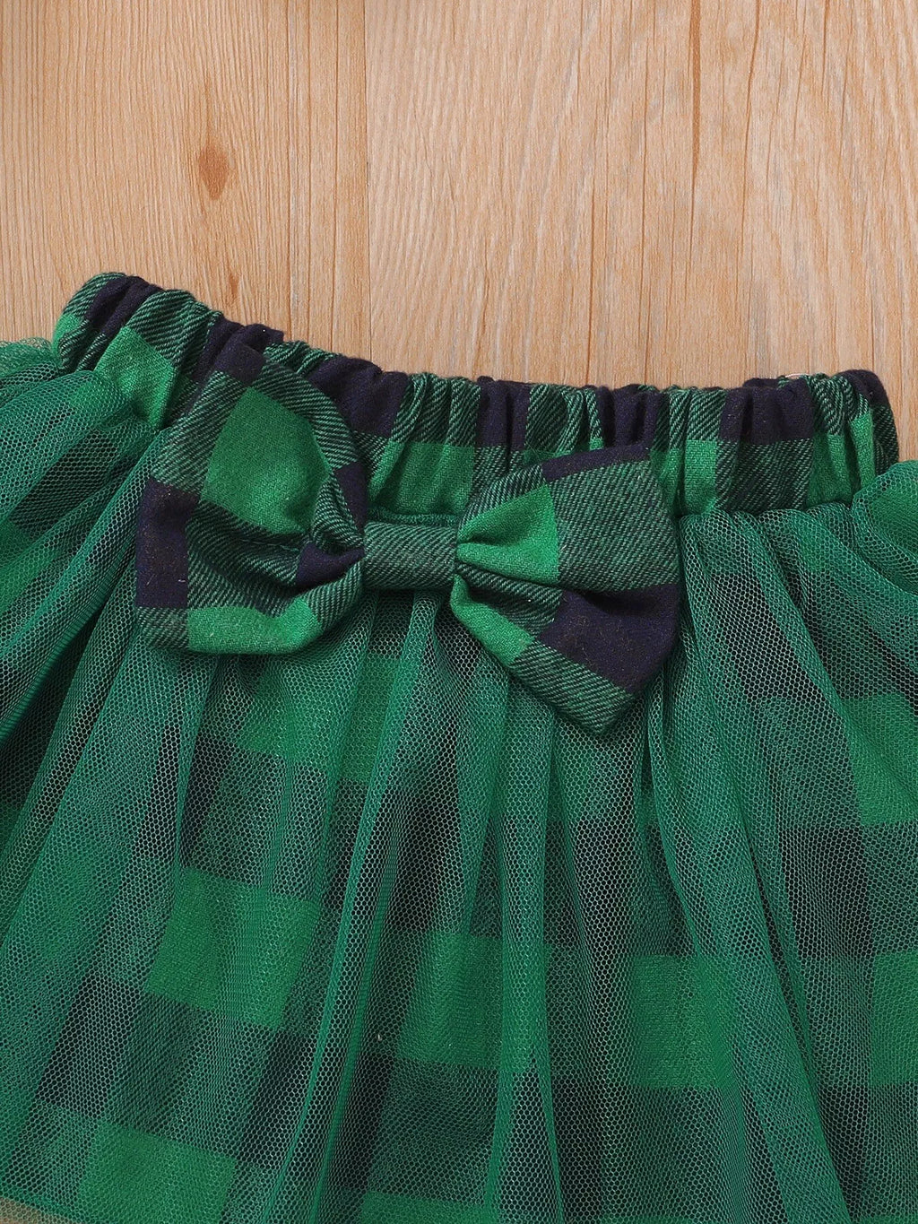 Close-up of the green plaid skirt waistband, bow and tulle overlay.