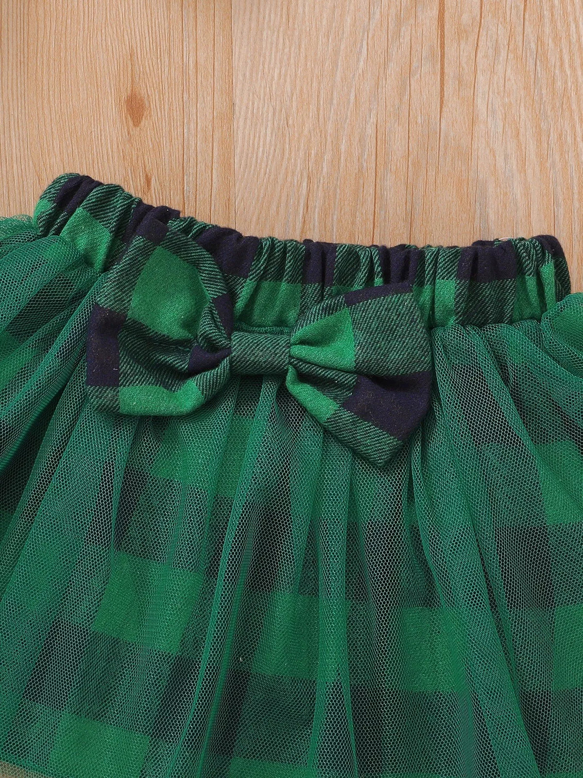 Close-up of the green plaid skirt waistband, bow and tulle overlay.