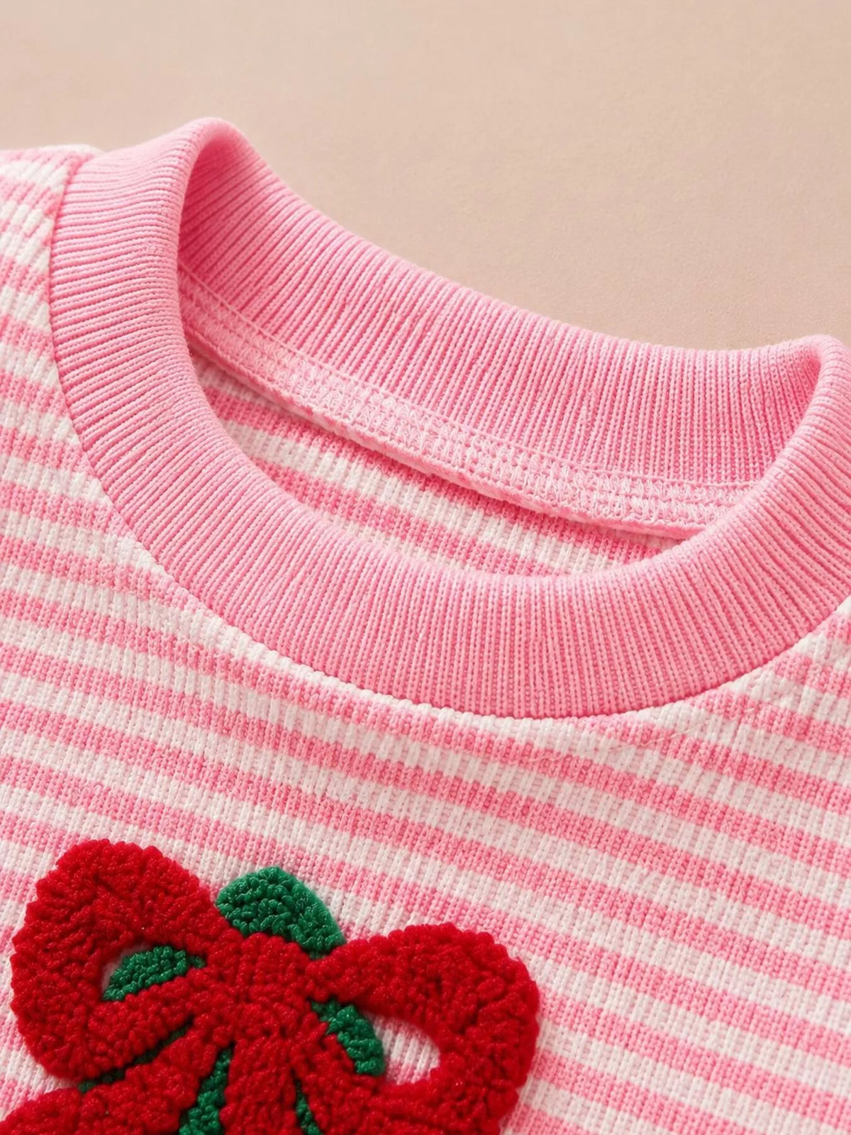 Pink ribbed neckline and red bow detail on the striped Christmas pajama top