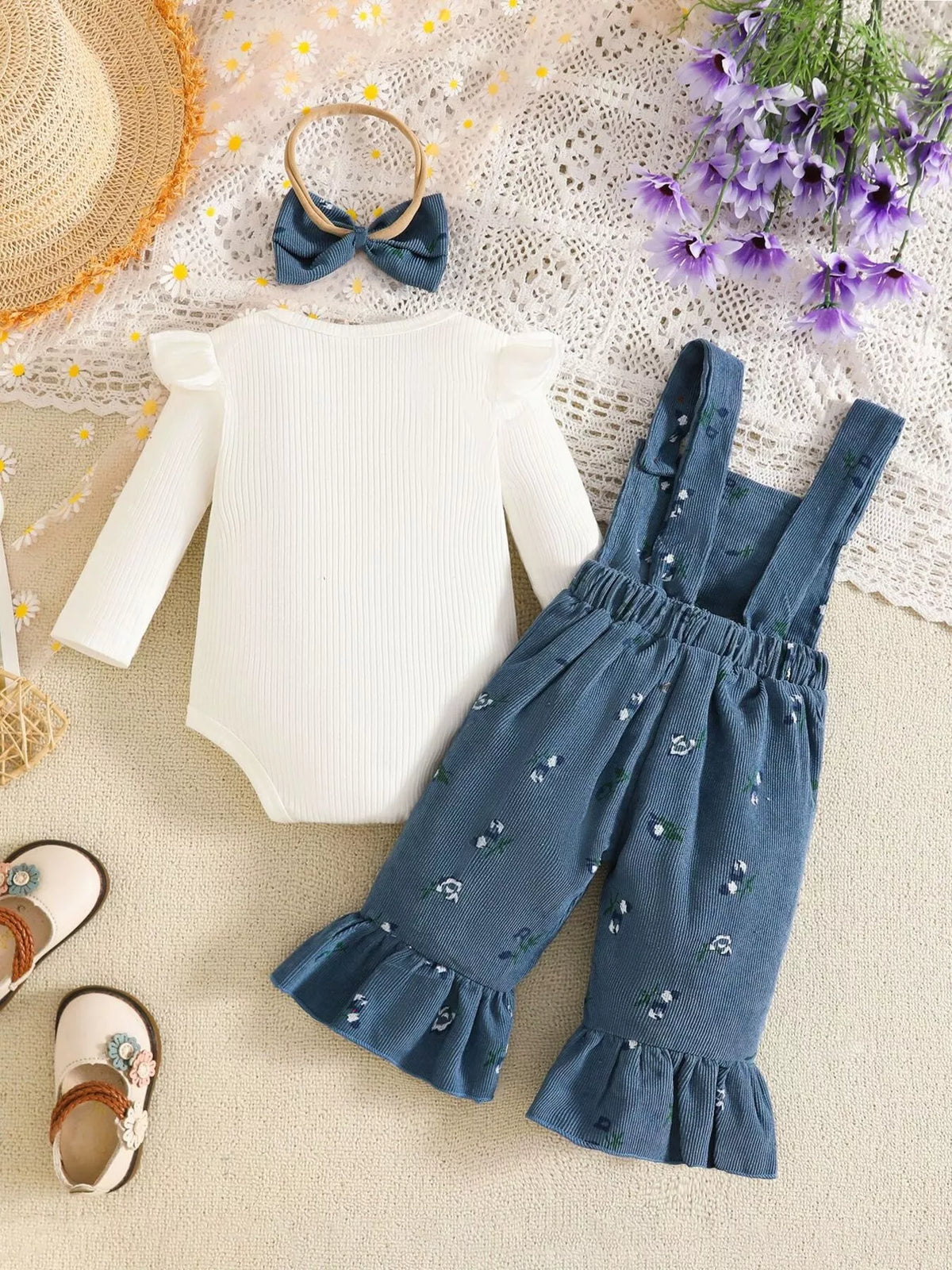 White ribbed baby bodysuit with blue bow-accented overalls and matching headband displayed flat