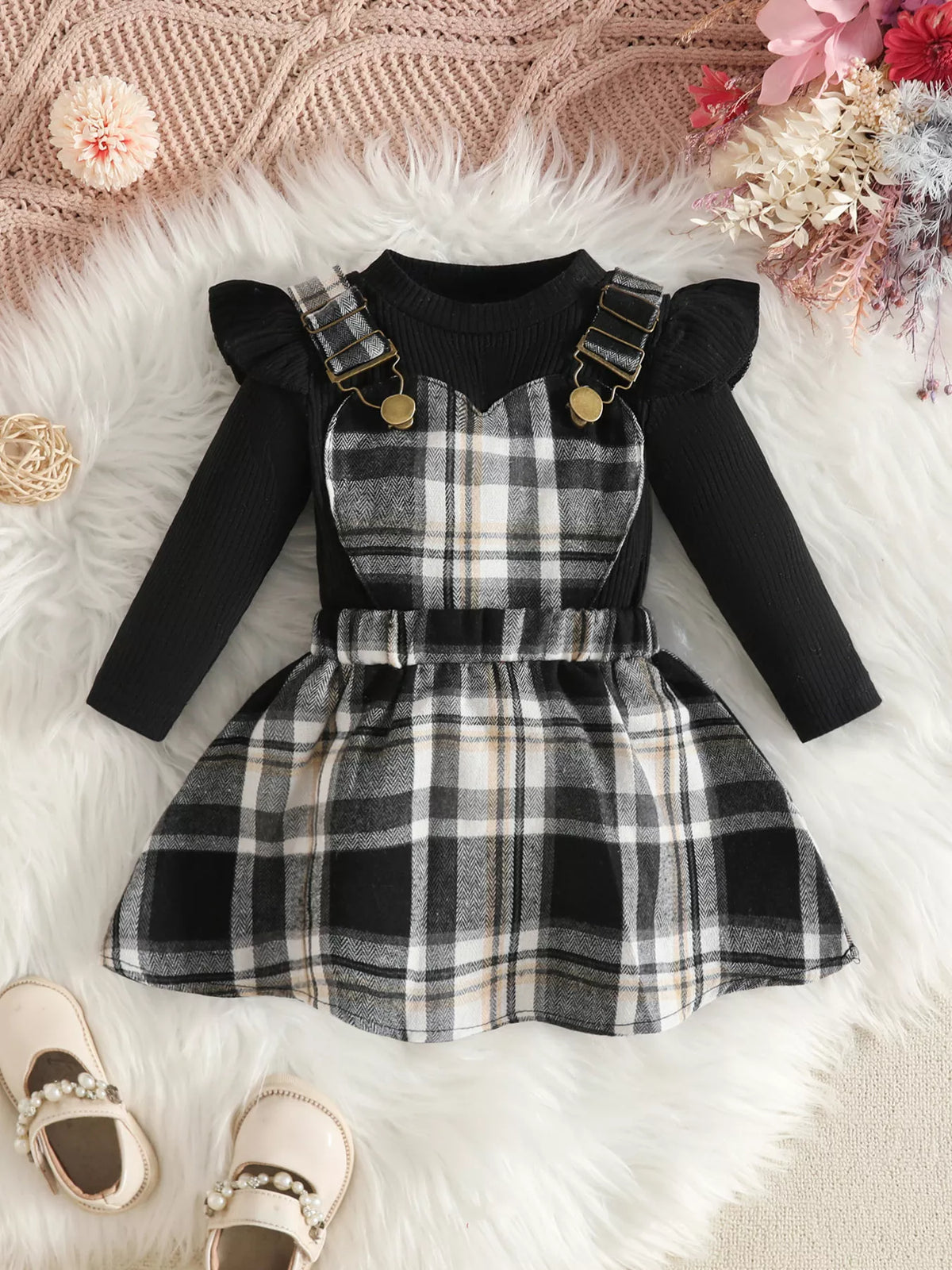 Black ruffle-shoulder top paired with a black-and-white plaid suspender skirt.