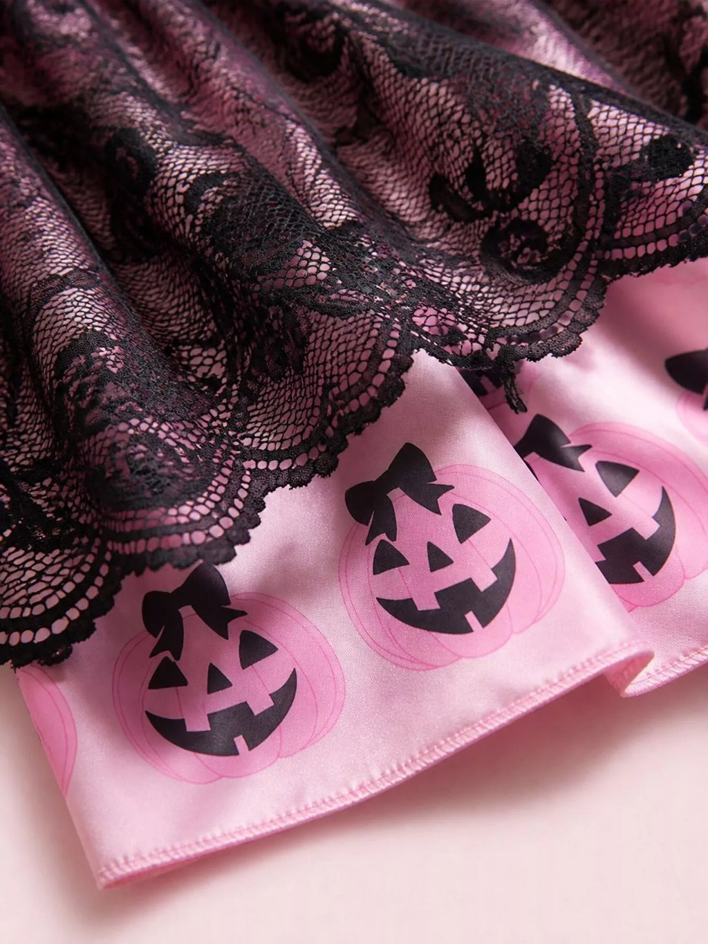 Close-up of scalloped black lace over the pink pumpkin-print skirt border.