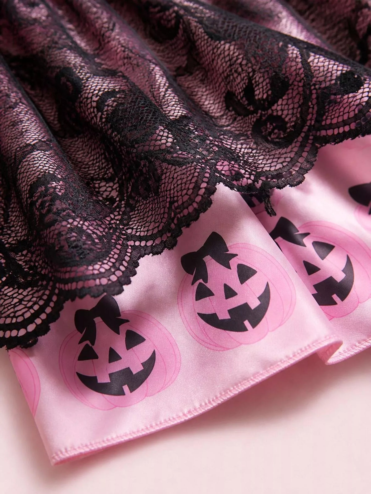 Close-up of scalloped black lace over the pink pumpkin-print skirt border.