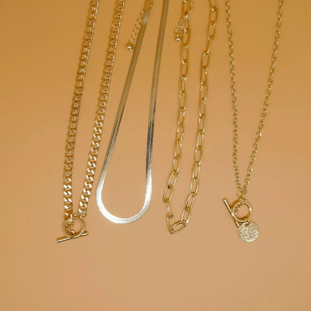 Four layered gold-tone necklaces with coin pendant and mixed chain styles — detail view