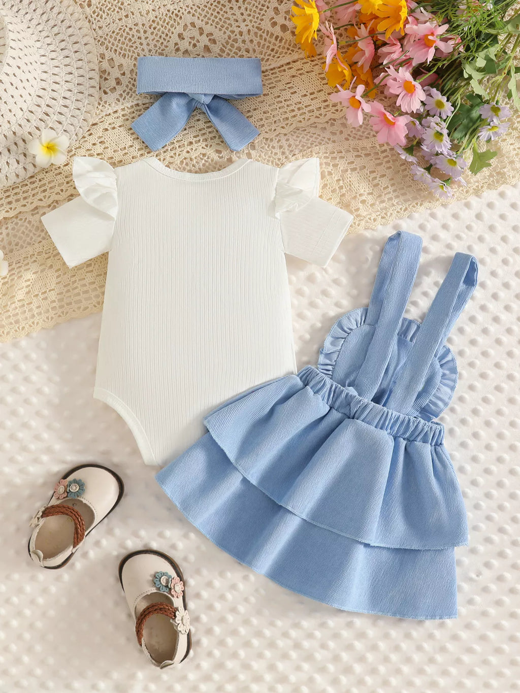 Back flat lay of the white bodysuit, light blue tiered suspender skirt and headband.