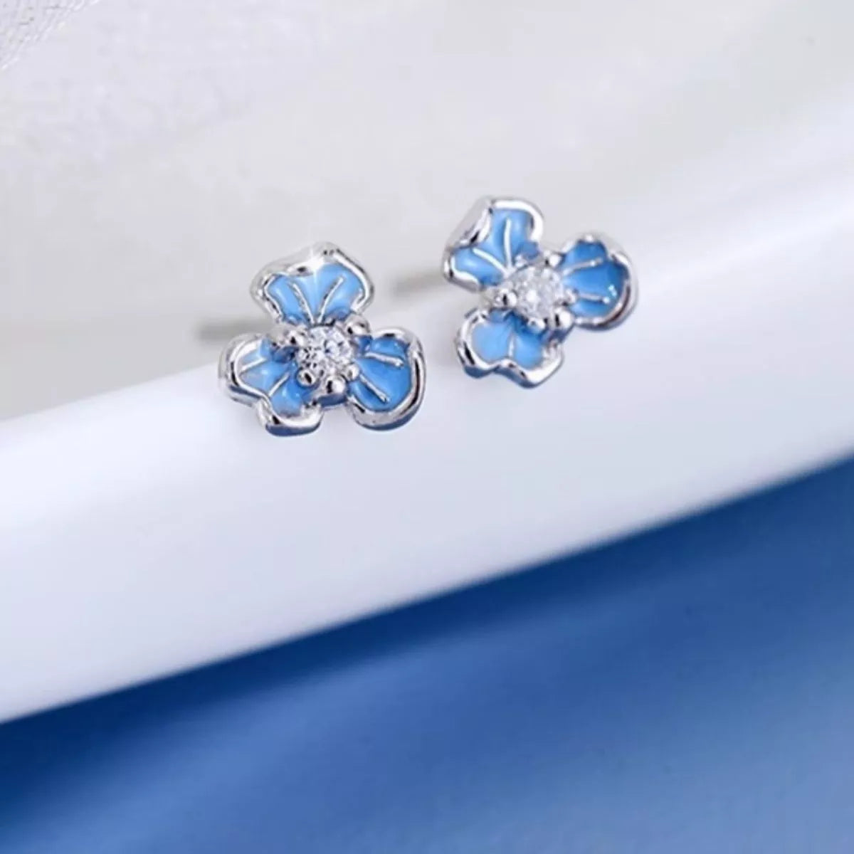 Silver-tone flower stud earrings with blue stones — detail view
