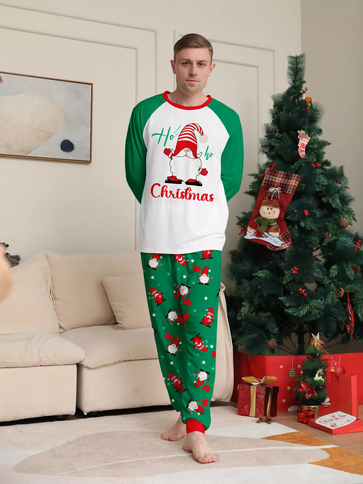 Man modeling a white Christmas graphic top with green sleeves and green printed pajama pants.