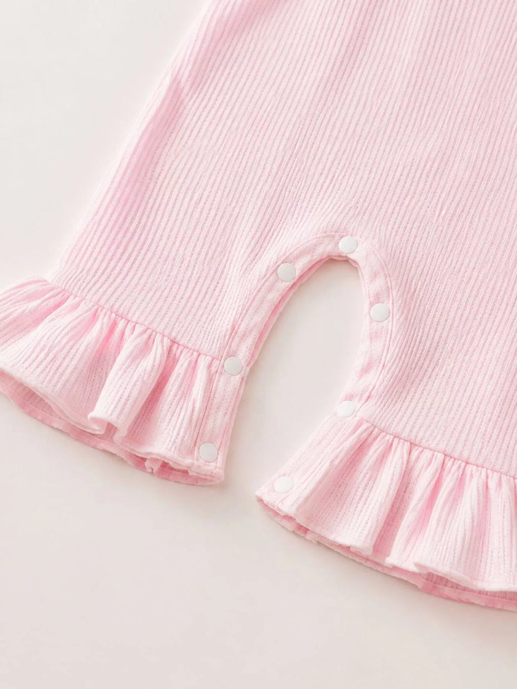 Close-up of the pink romper's gathered ruffle leg hems.