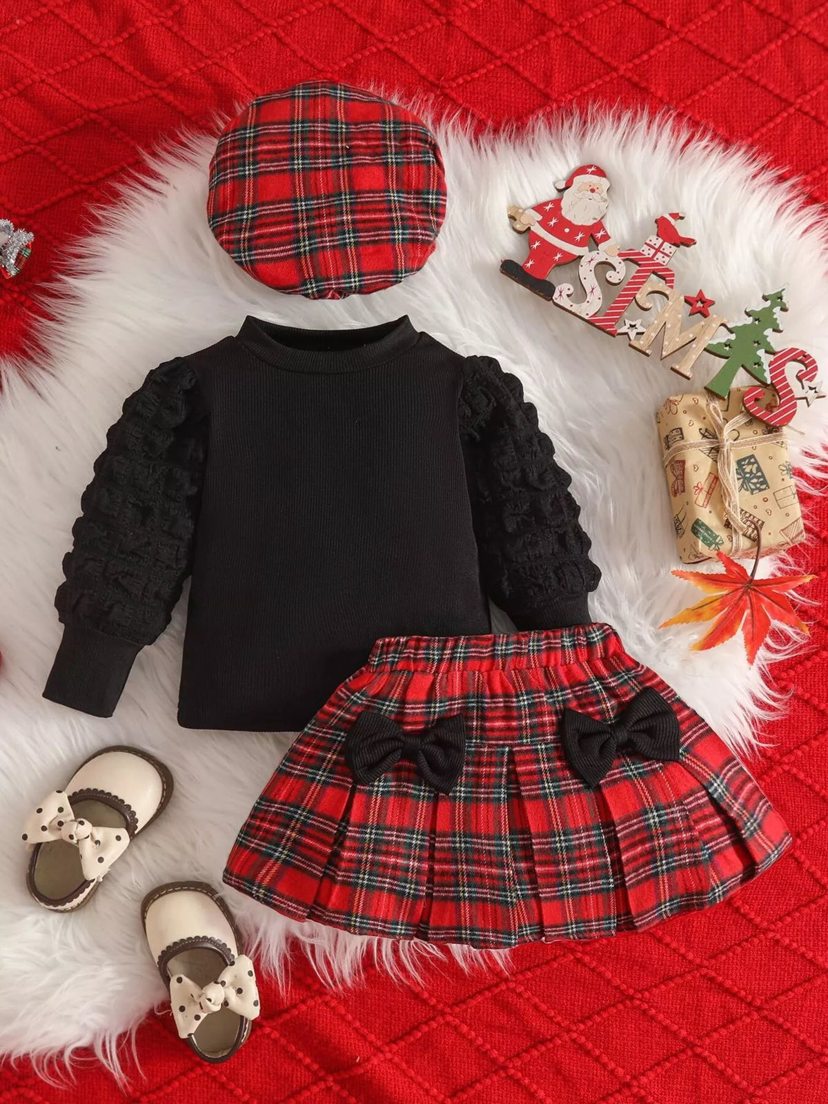 Black baby top with textured sleeves, red plaid skirt and matching plaid beret.