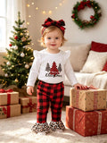 Toddler wearing a white Christmas tree graphic top, red plaid pants and plaid headband.