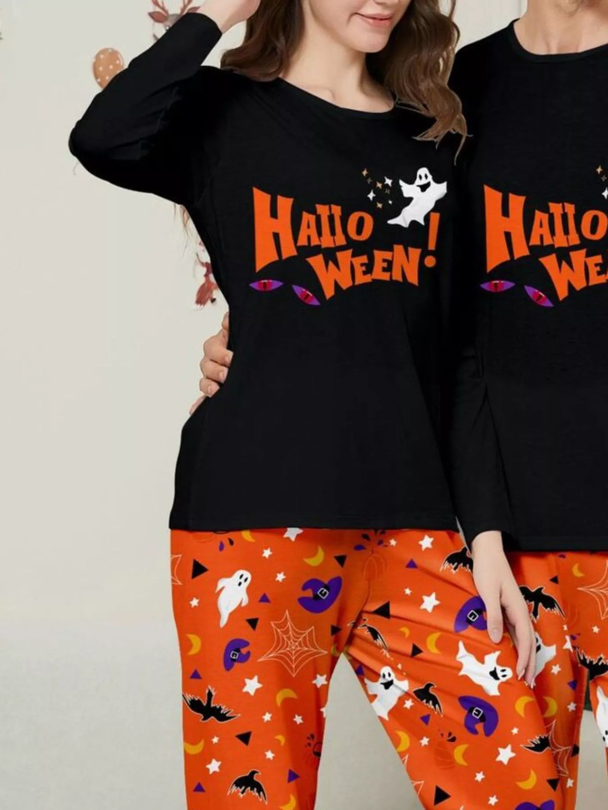 Woman wearing a black Halloween graphic top and orange printed pajama pants.