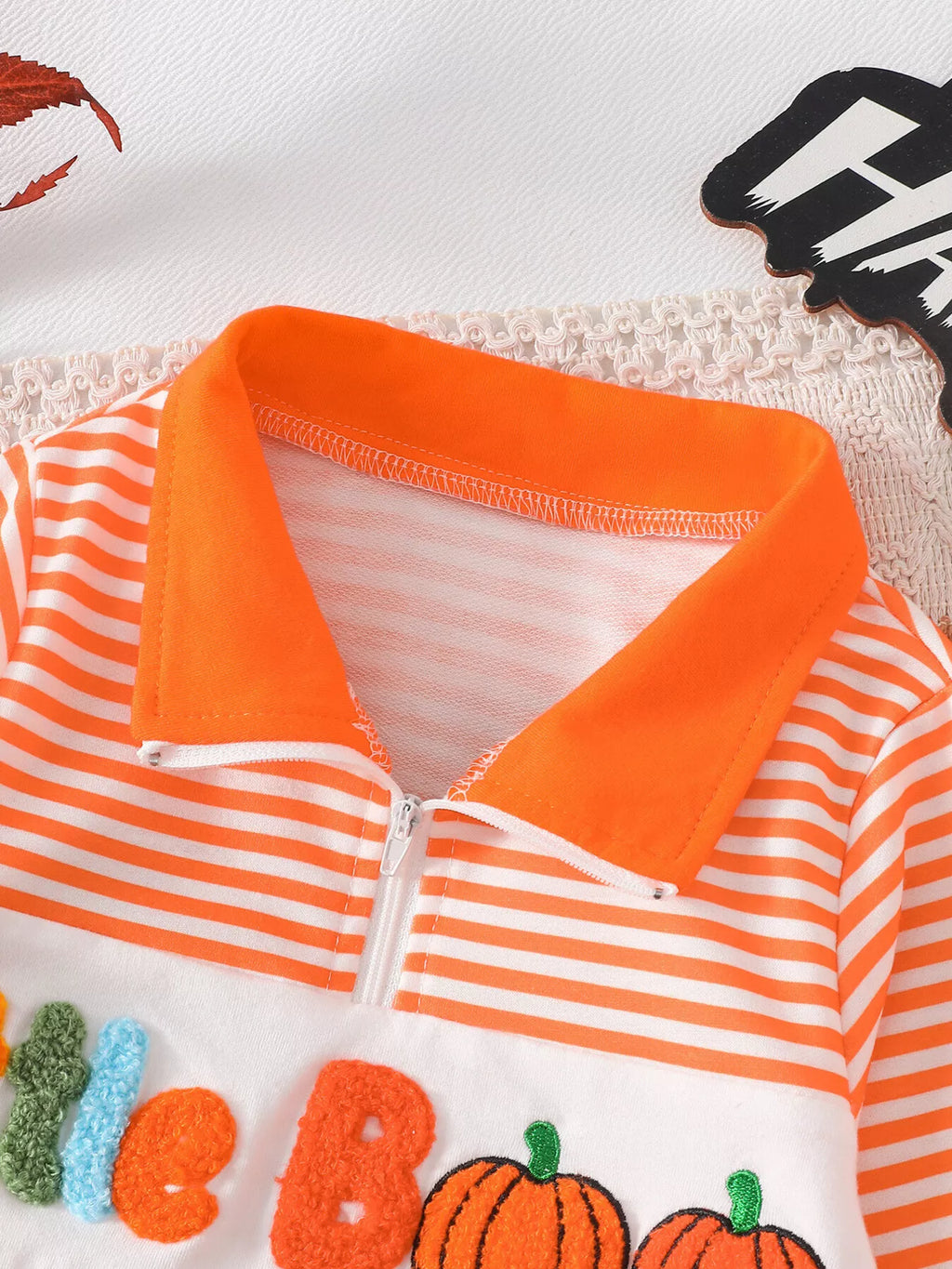 Close-up of the orange collar and zipper on the orange striped top.