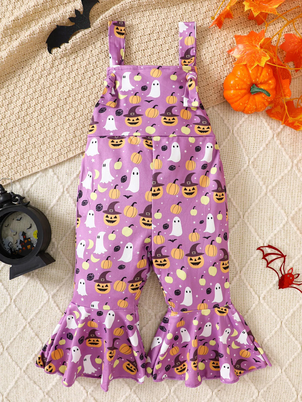 Purple Halloween-print suspender overalls with gathered waist and flared ruffle legs.