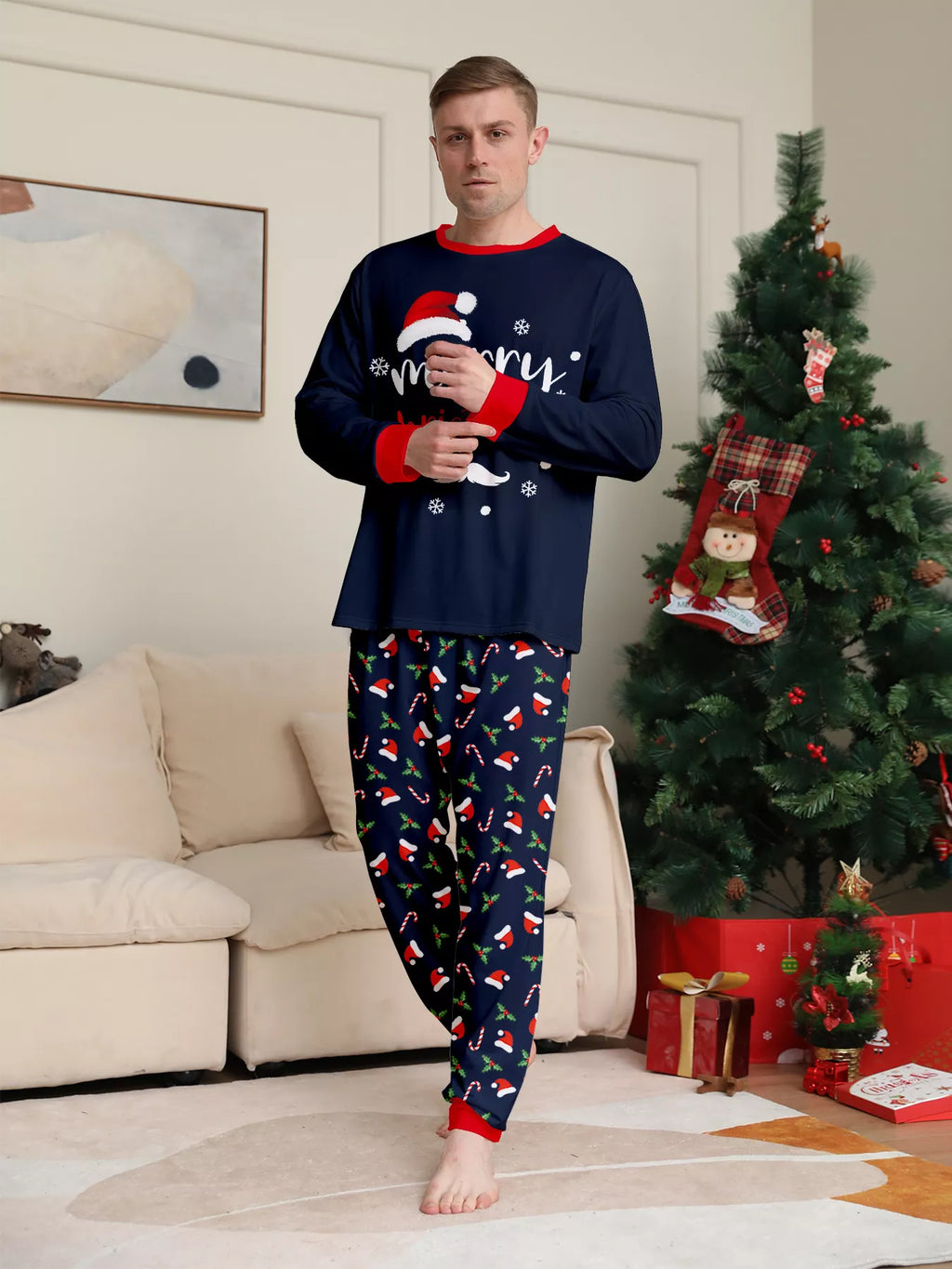 Man modeling the navy Merry Christmas pajama set beside a Christmas tree.