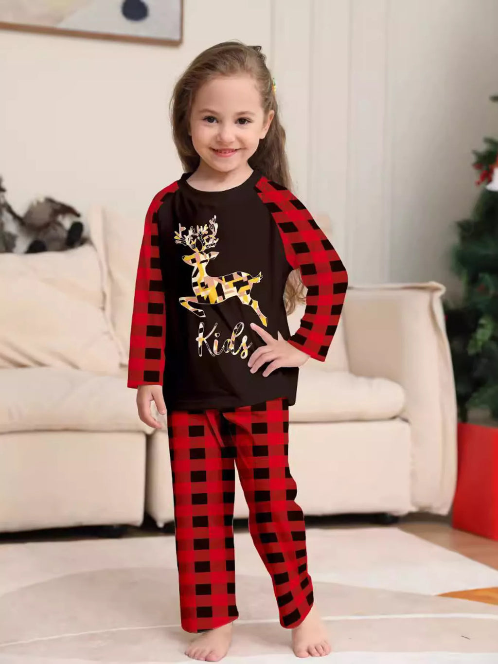 Child wearing a black reindeer graphic top with red plaid sleeves and pants.