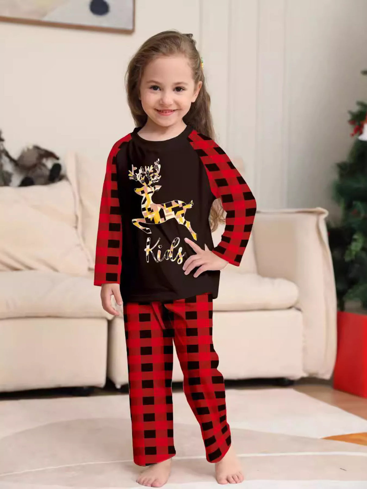 Child wearing a black reindeer graphic top with red plaid sleeves and pants.