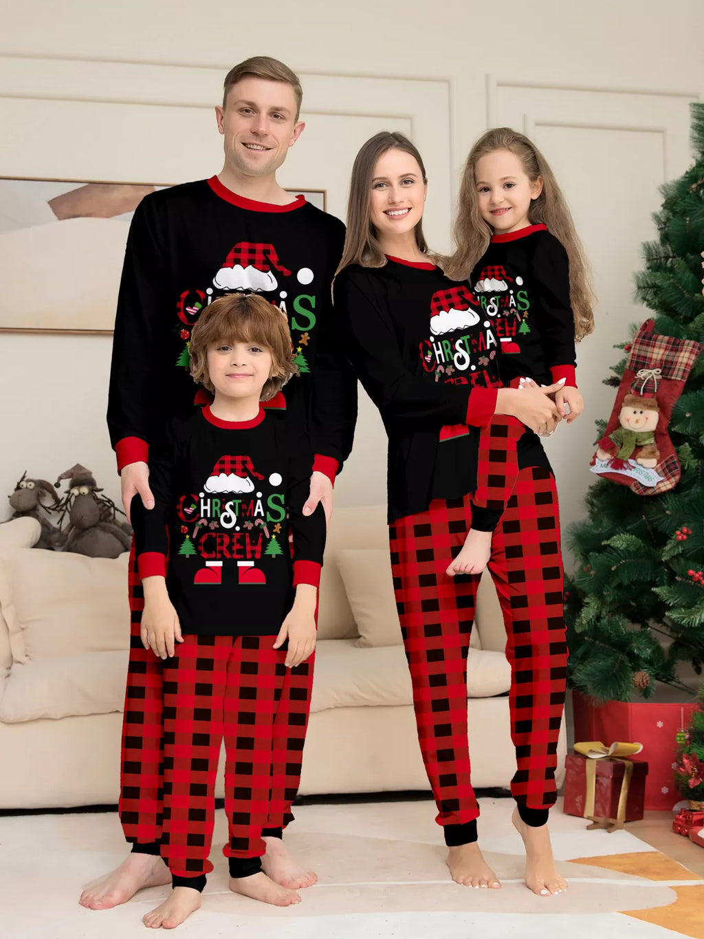 Family modeling matching black Christmas graphic tops and red plaid pajama pants.