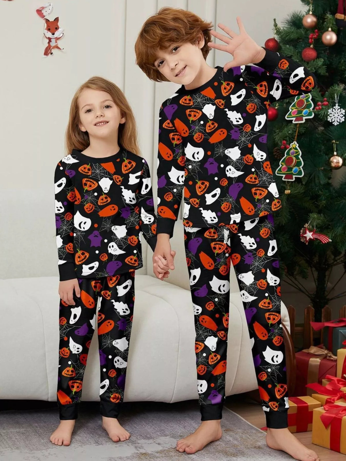 Black matching family pajamas with colorful Halloween ghost and pumpkin print worn by two children