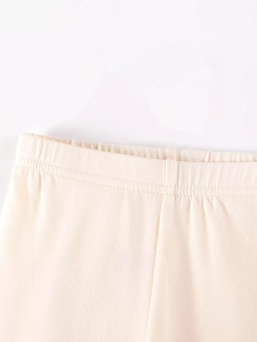 Close-up of the cream leggings' elastic waistband.