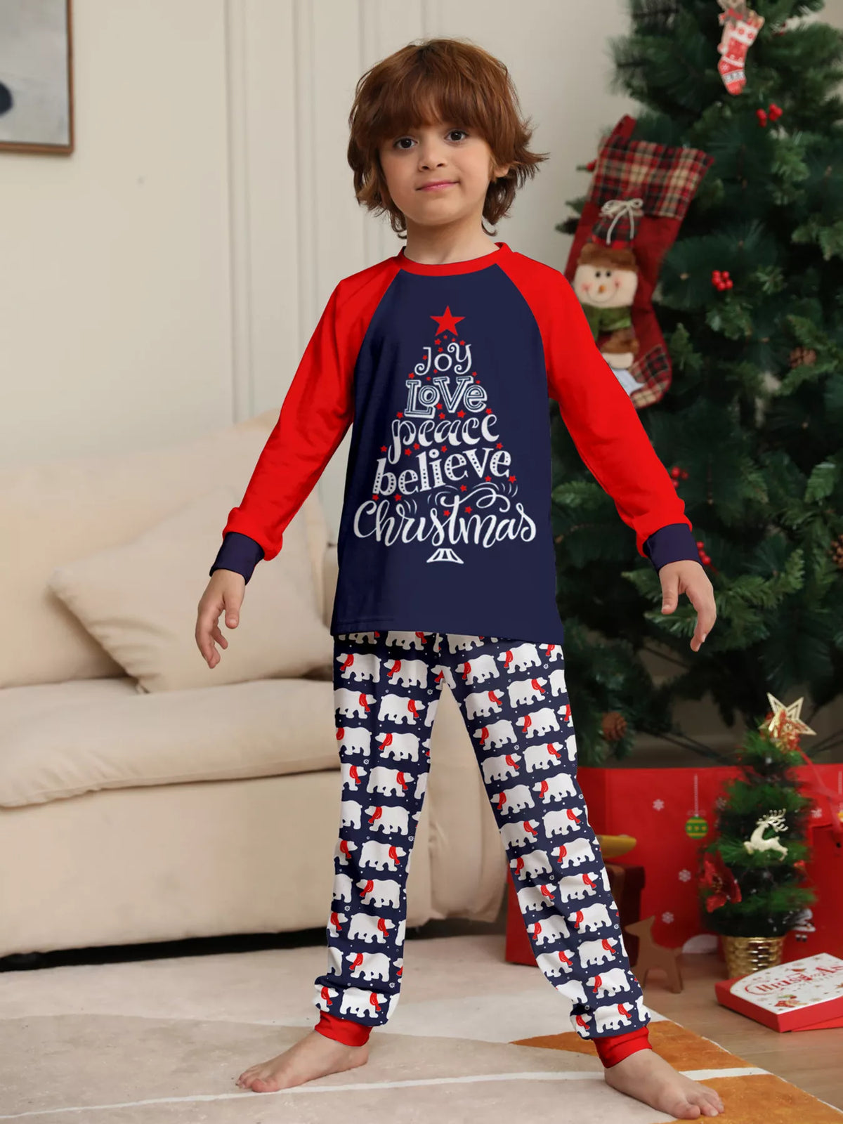 Navy and red Christmas graphic pajama top with matching festive-print pants worn by a child