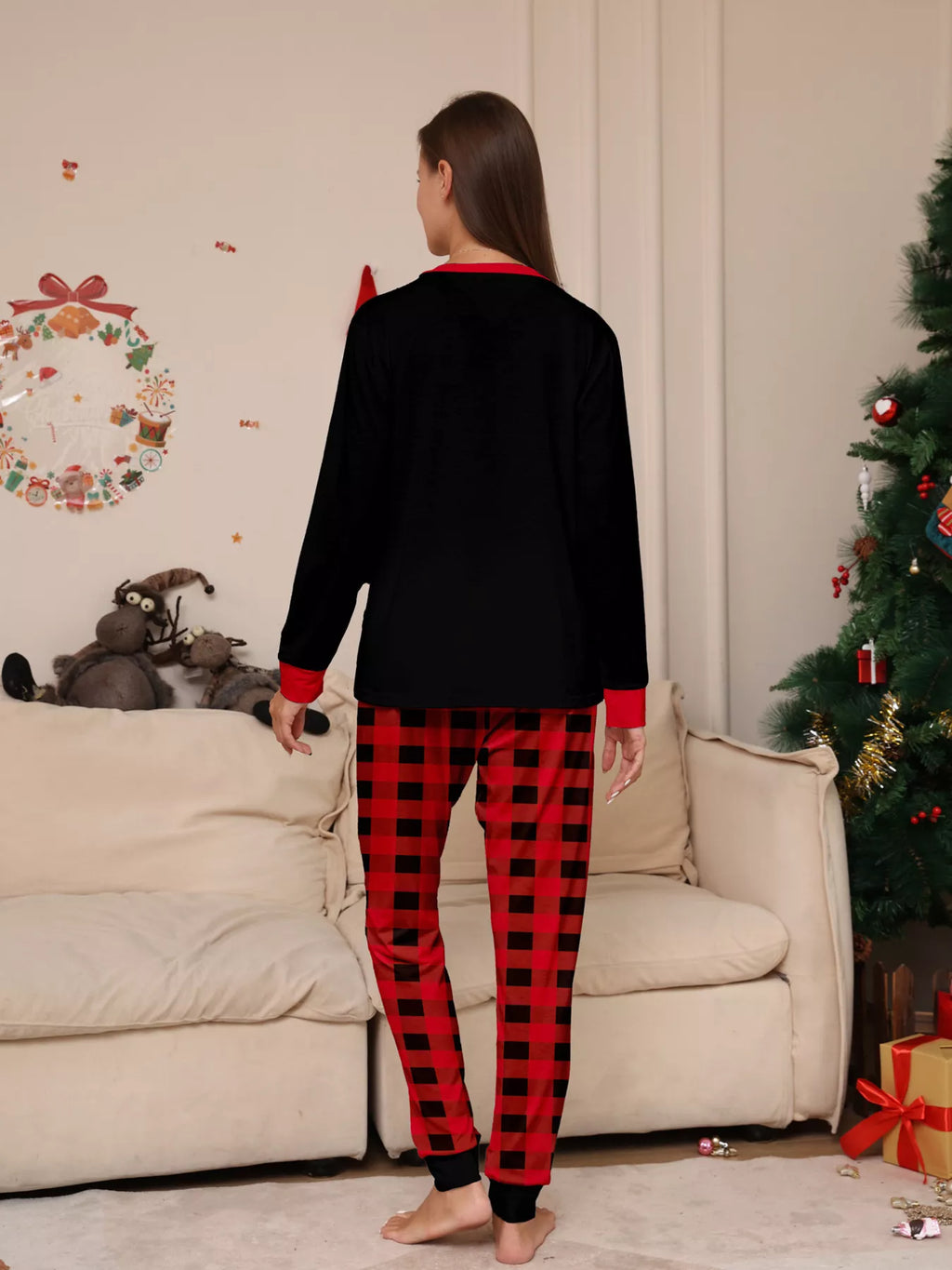 Back view of a woman wearing the black top and red plaid pajama pants.