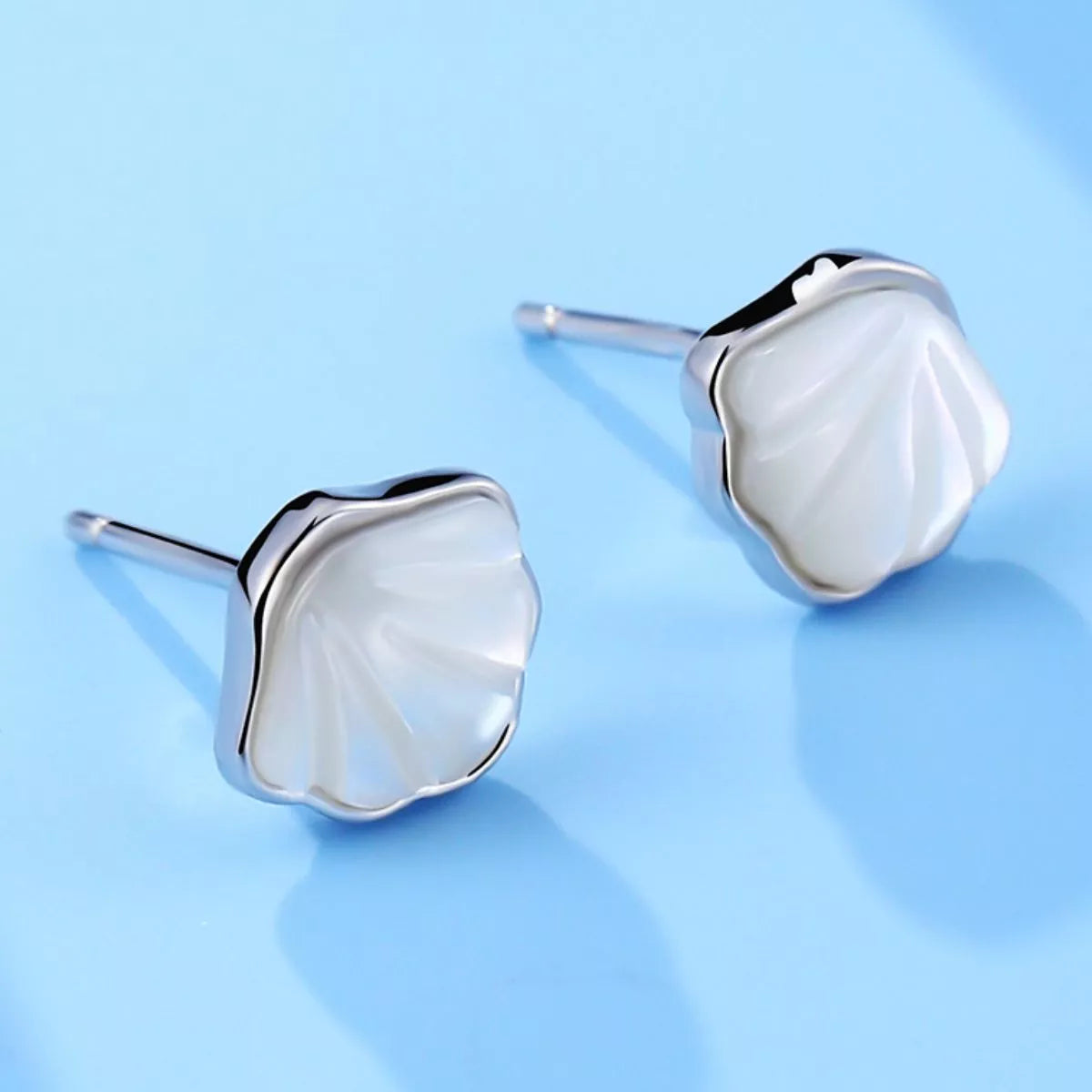 Silver-tone shell-shaped stud earrings with white centers — detail view