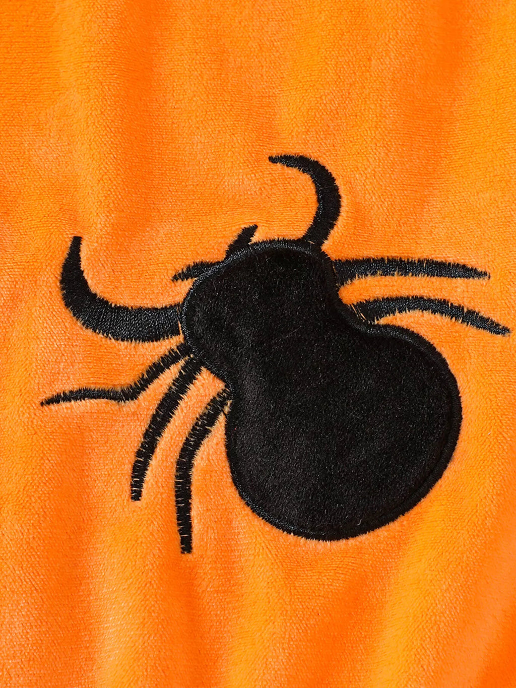 Black spider applique on orange baby bodysuit fabric