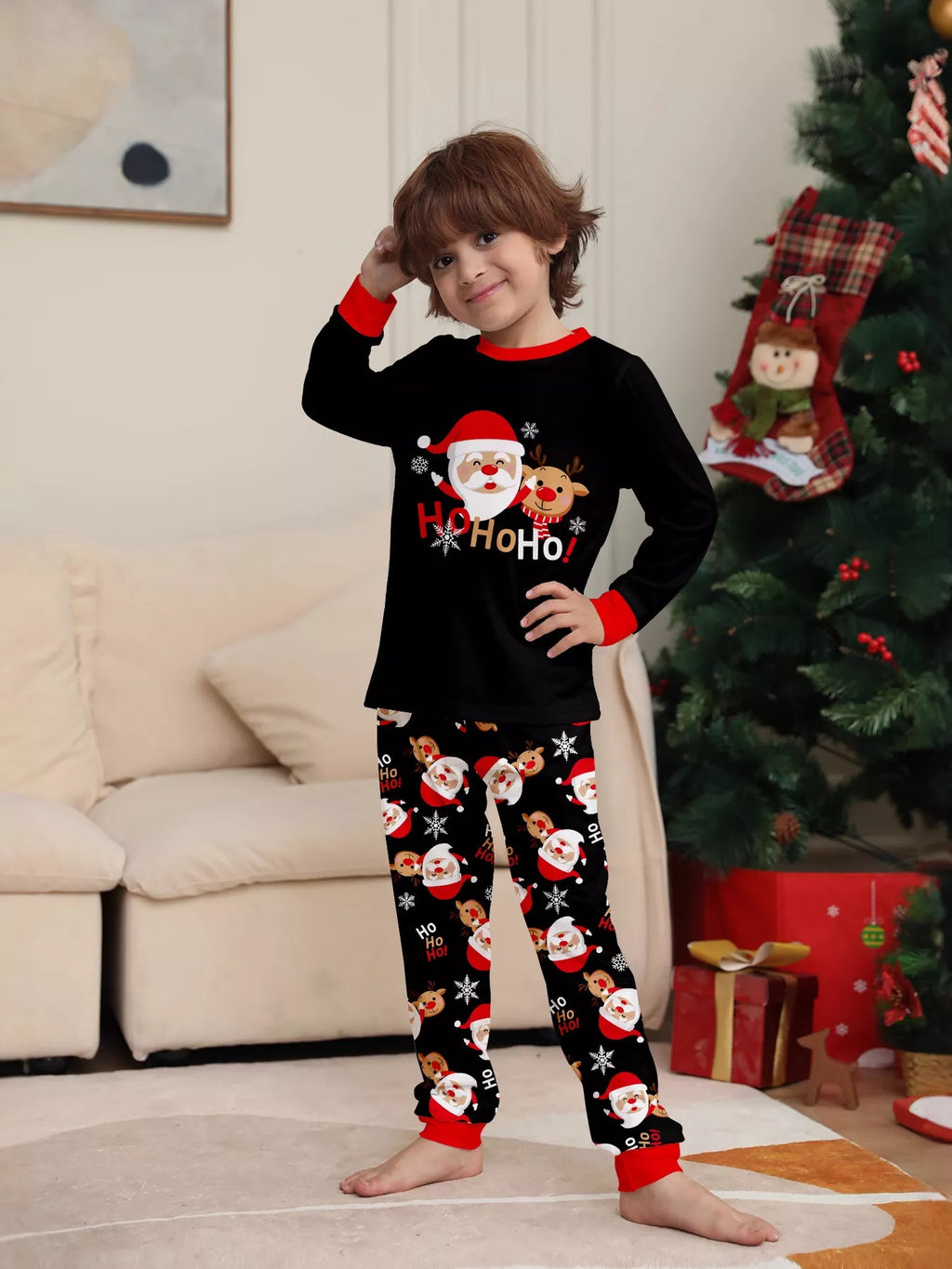 Child modeling the black Ho Ho Ho Santa top and Santa-print pants.
