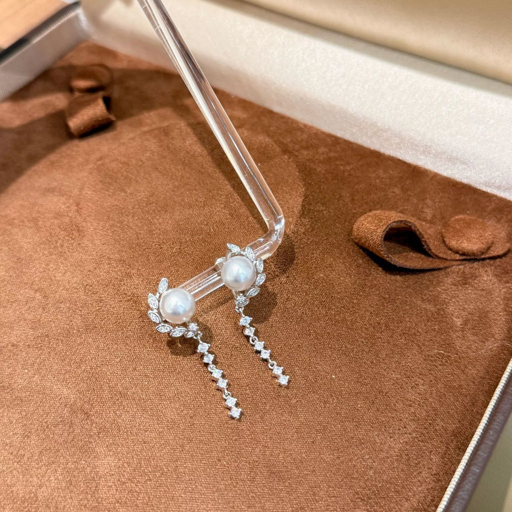 Pearl-like bead drop earrings with long dangling clear stone chains — detail view