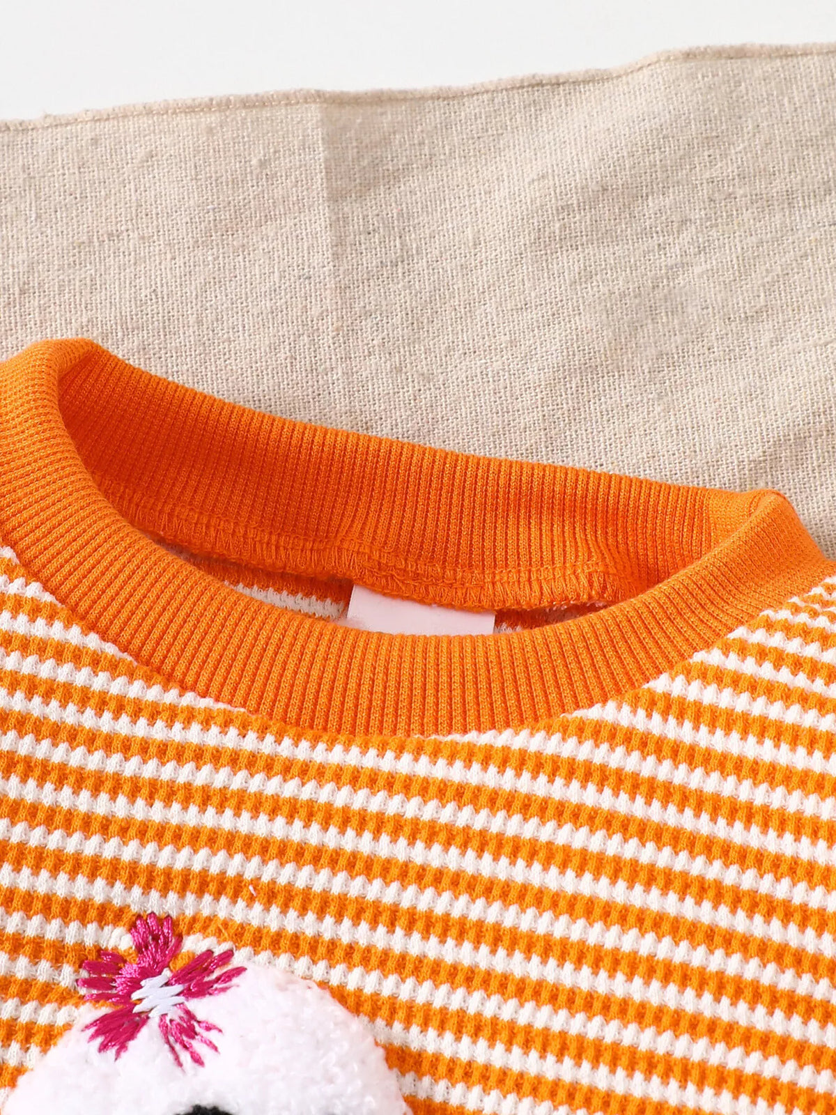 Orange ribbed crew neckline of the striped ghost pajama top
