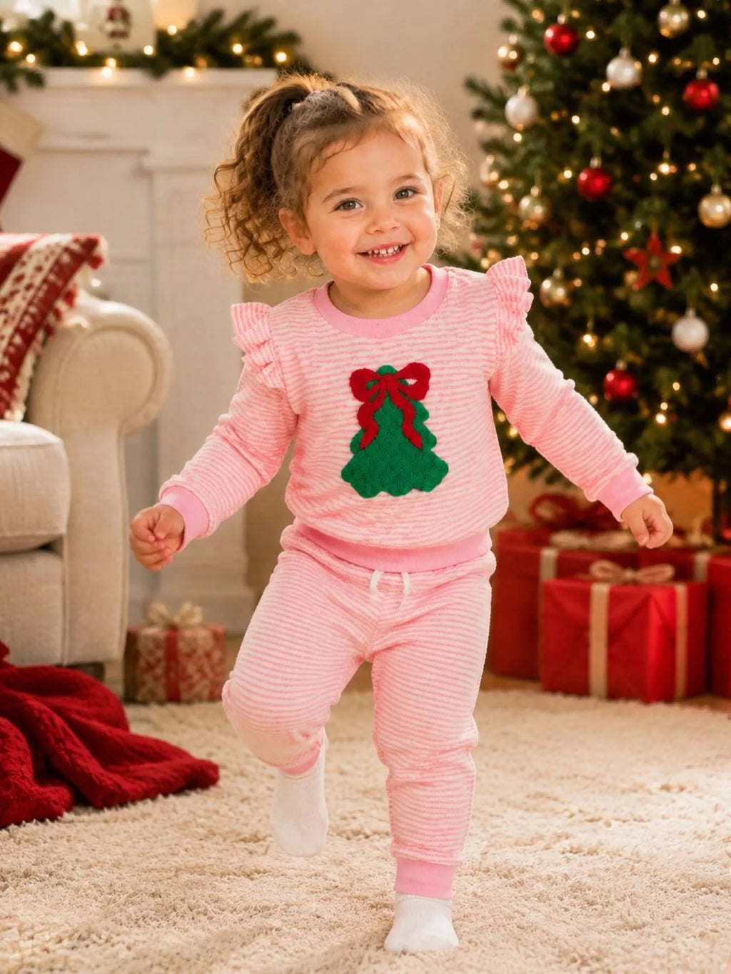 Pink striped Christmas-tree patch pajama top and ruffle-trim pants worn by a child