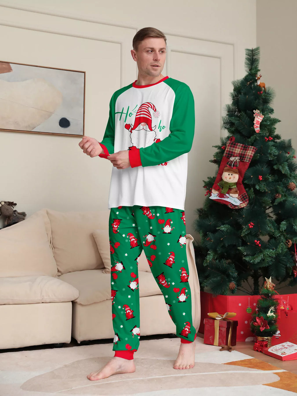 Man modeling a white Christmas graphic top with green sleeves and green printed pajama pants.