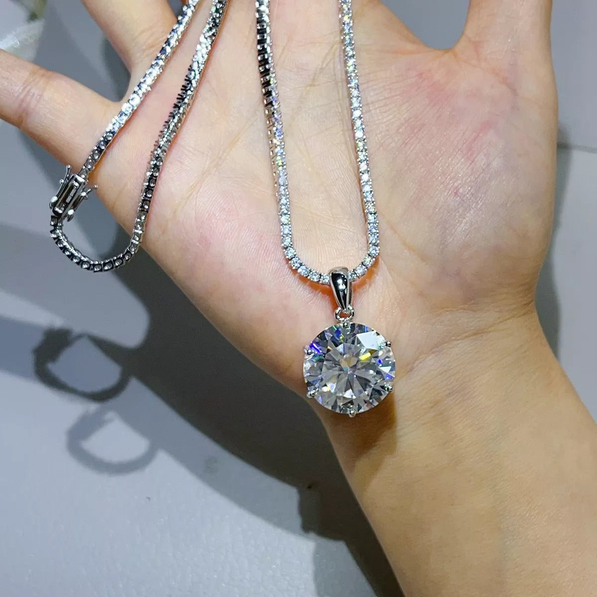 Silver-tone necklace with a round clear stone pendant — detail view
