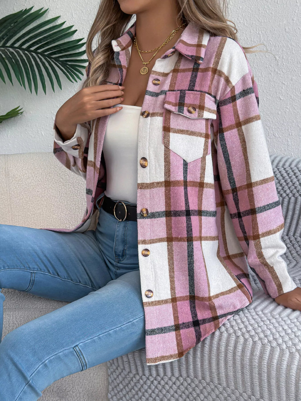 Pink plaid button-down shacket with chest pockets, modeled seated with jeans.