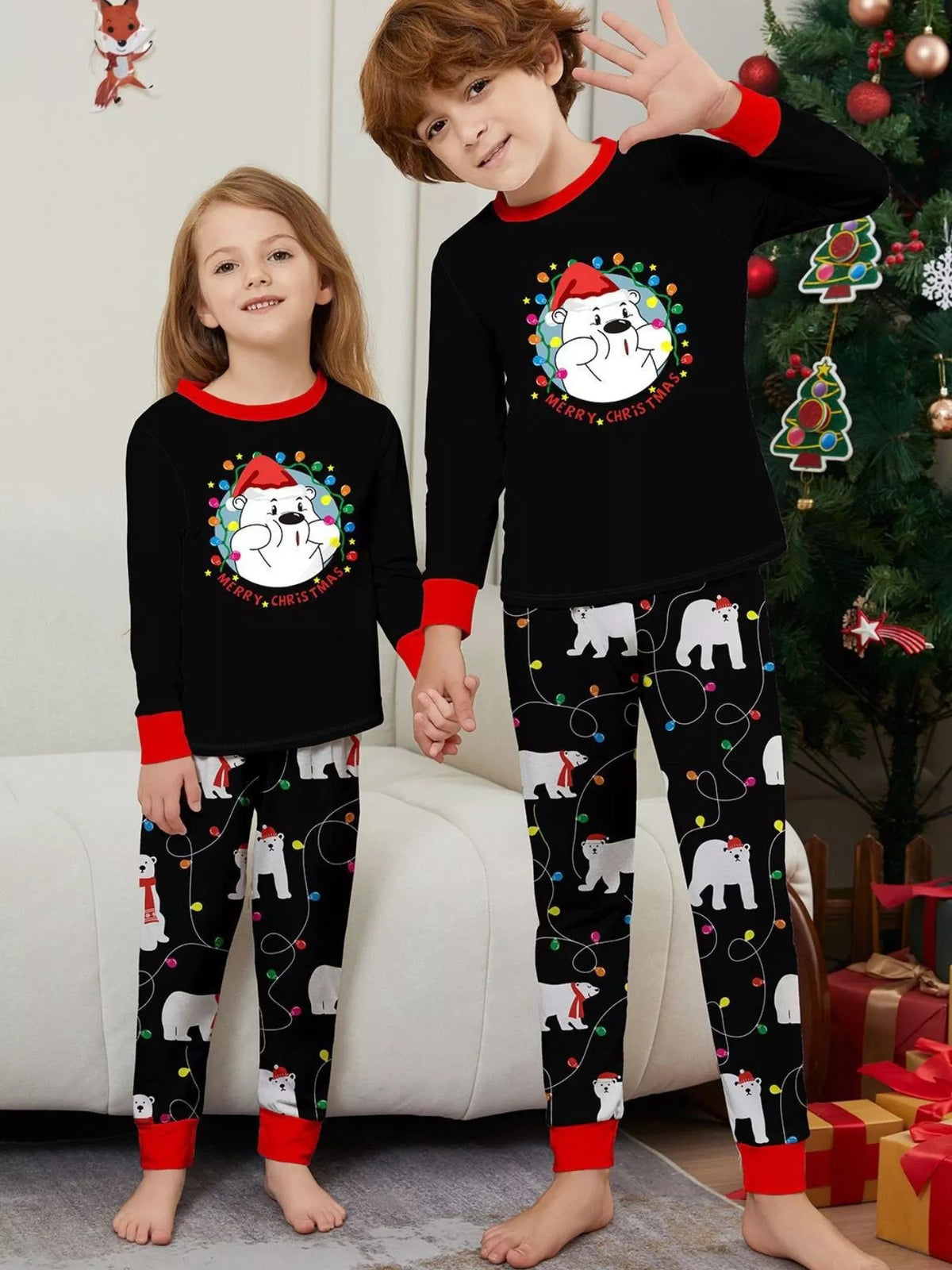 Two children wearing matching black Christmas tops and polar-bear-print pajama pants.