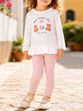 Children’s white polka-dot bear graphic ruffle-hem top with pink leggings worn by a child