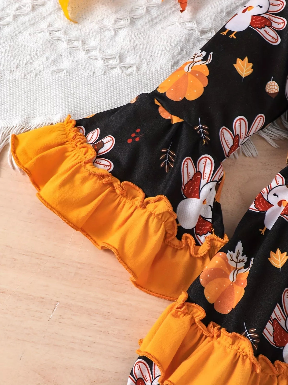 Orange ruffle cuff and turkey-print sleeve of the black dress