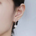 Silver-tone hoop earrings with round halo stone drops — detail view