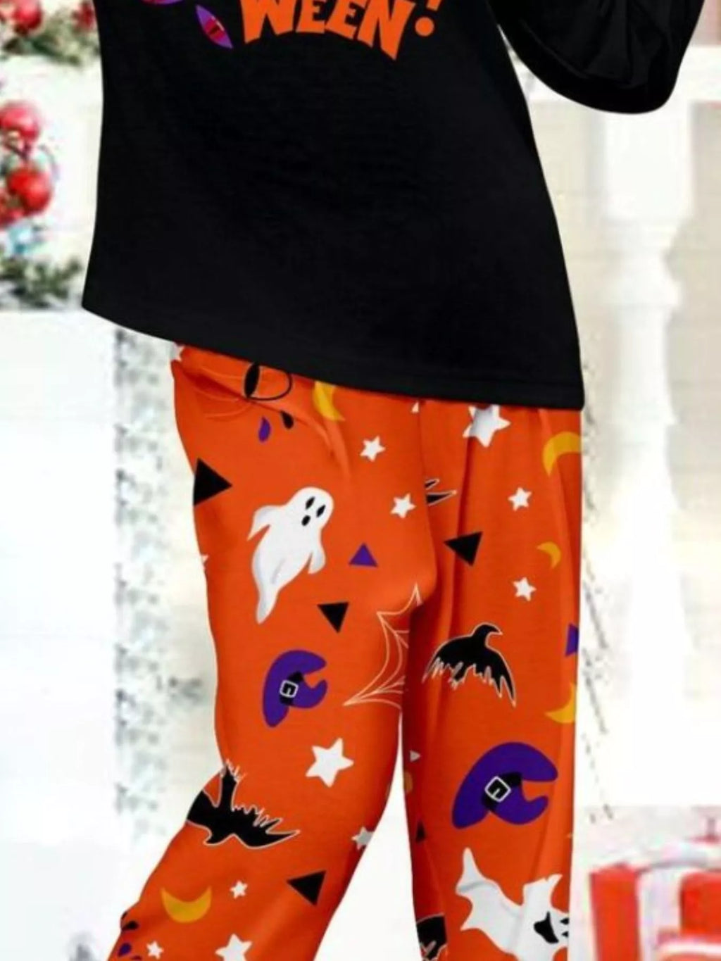 Close-up of a child's orange Halloween pajama pants and black graphic top.