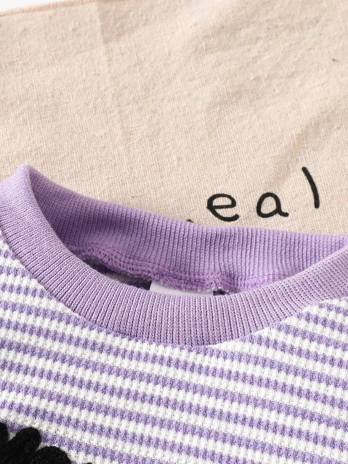 Purple ribbed crew neckline of the striped pajama top